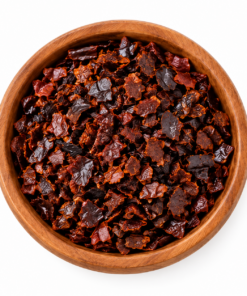 Ancho chili gebroken in houten kom op witte achtergrond