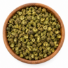 Groene Szechuanpeper in een ronde houten kom op een witte achtergrond.