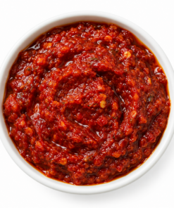 Rode harissa peperpasta in een witte ronde kom