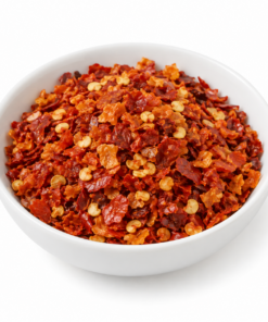 Scotch Bonnet chilivlokken in een wit rond bakje op witte achtergrond