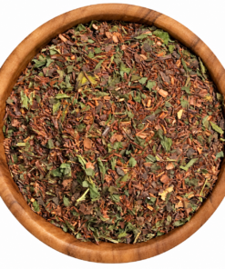 Rooibos met munt en cacaodoppen in een ronde houten kom op een witte achtergrond.